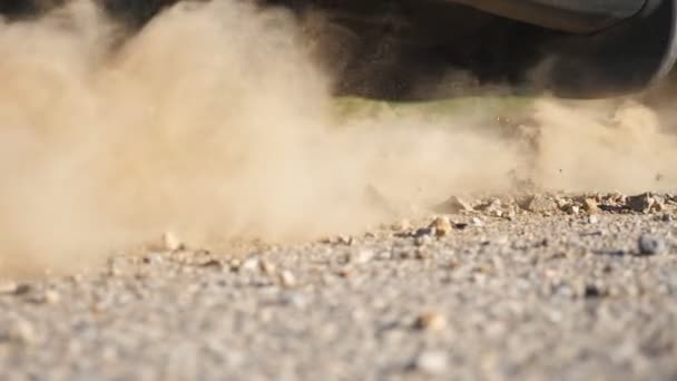 Die Räder des Autos rutschen während der Fahrt auf einer asphaltierten Straße. Kleine Steine und Schmutz fliegen unter dem Autoreifen hervor. Fahrzeug schnell in Bewegung. Begriff Burnout. Zeitlupe — Stockvideo