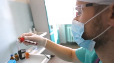 Bilim adamı Coronavirus 'a kan örneği vererek test tüpünü inceliyor. Koruyucu eldivenli laboratuvar çalışanı kan örneklerini COVID-19 'a test ediyor. Corona virüsü salgınından korunan sağlık ve güvenlik hayatı kavramı
