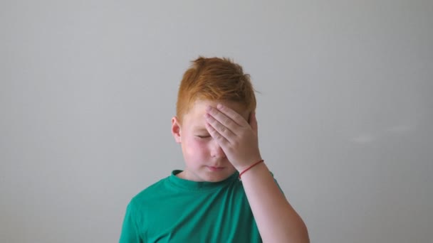 Ένα νεαρό αναστατωμένο παιδί να αγγίζει το πρόσωπό του εκφράζοντας μια απελπισία. Κοντινό πλάνο συναισθήματα του αρσενικού παιδιού με θλιβερή έκφραση μέσα. Πορτρέτο του σοβαρού κοκκινομάλλη αγόρι με φακίδες εσωτερική. Αργή κίνηση — Αρχείο Βίντεο