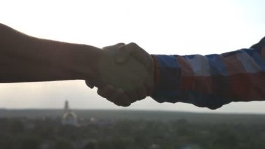 Çatıda buluşan ve dışarıda birbirini selamlayan gençlerin yakınlaşması. Şehir planında el sıkışan iki arkadaş. Arkadaşlar arasında dostça bir el sıkışma. Arkadaşlık kavramı. Yan görünüm Yavaş çekim