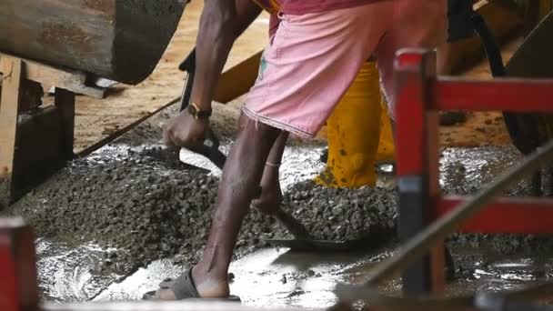 Мужские индийские руки собирают мокрый цемент лопатами в кучу на строительной площадке. На строительной площадке работают местные неузнаваемые строители. Концепция будущего проекта. Закрыть Медленное движение — стоковое видео