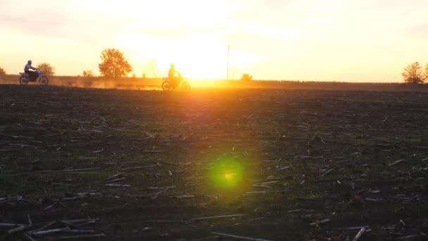 Motorrijders die op hun motor door het veld rijden en stofsporen achterlaten. Vrienden hebben actieve rust buiten rijden krachtige motorfietsen bij zonsondergang. Motorrijders genieten van de reis. Extreem sportconcept — Stockvideo