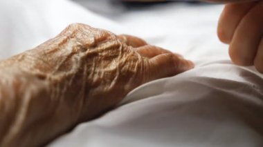 Annesinin şefkatini ya da sevgisini gösteren elini nazikçe okşayan tanınamaz bir kadın. Klinikte yatan yaşlı bir annenin kırışık kolunu rahatlatan kızı. Kız, eski ailesine destek oluyor. Ayrıntılı görünüm