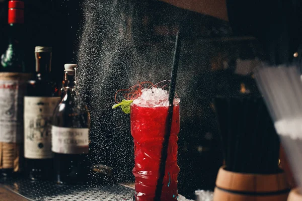 Barkeeper Hände, die den Saft in das mit alkoholischen Getränken gefüllte Cocktailglas auf dem dunklen Hintergrund streuen — Stockfoto