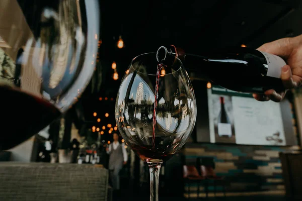Наливання червоного вина з пляшки в келих винограду — стокове фото
