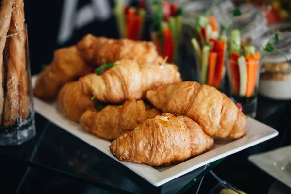 Lots of fresh croissants on a white plate on the buffet in the restaurant — ストック写真