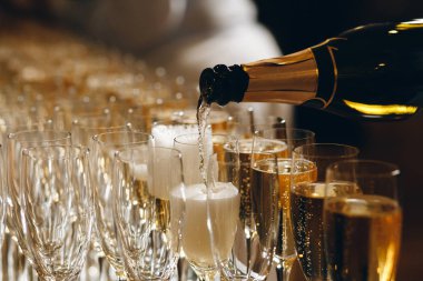 Barmen şarap bardaklarına şampanya ya da şarap dolduruyor açık hava düğün töreninde masada.