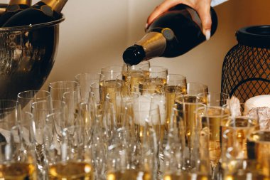 Barmen şarap bardaklarına şampanya ya da şarap dolduruyor açık hava düğün töreninde masada.