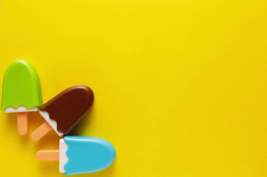 Renkli ve çeşitli plastik oyuncaklar. Sarı arka planda bebekler için numaralar var. Yerleşim planı. Metin için boş alan. Minimalizm.