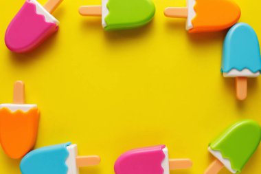 Renkli ve çeşitli plastik oyuncaklar. Sarı arka planda bebekler için numaralar var. Yerleşim planı. Metin için boş alan. Minimalizm.