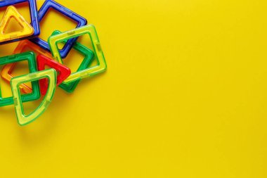 Çocukların manyetik tasarımcısı ya da inşaatçısı. Detaylar, sarı arkaplanda geometrik şekiller. Düz yat, boşluğu kopyala