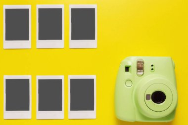 Modern yeşil polaroid kamera, sarı arka planda fotoğraf. Üst manzara, yumuşak minimum düz konum kompozisyonu. Turizm konsepti. metin için kopyalama alanı ile.