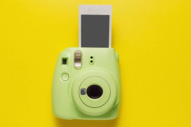 Modern yeşil polaroid kamera, sarı arka planda fotoğraf. Üst manzara, yumuşak minimum düz konum kompozisyonu. Turizm konsepti. metin için kopyalama alanı ile.