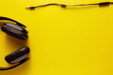 Sarı arkaplanda siyah kulaklığın üst görünümü.