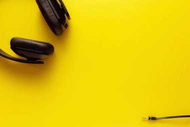 Sarı arkaplanda siyah kulaklığın üst görünümü.