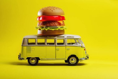 Sarı retro oyuncak araba. Sarı arka planda yemek burgeri dağıtıyor.