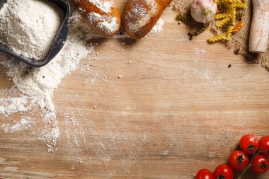 Un ürünleri kopyalama alanı olan ahşap bir masada. Un, makarna, oklavalı ekmek. Metin için boşluk olan üst görünüm