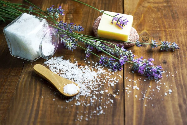 Spa massage setting with lavender flowers, soap and cosmetic salt on wooden background. — Stock Photo, Image