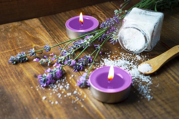Lavanta çiçekleri, kokulu aroma mumlar ve ahşap arka plan üzerinde kozmetik tuz ile Spa masaj ayarı.