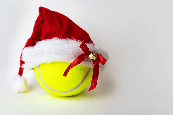 Noel ve Yeni Yıl kavramı, gri arka planda tenis topunda Noel Baba şapkası..