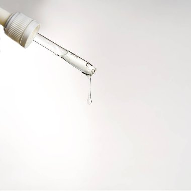 Serum damlası ya da gri arka planda hyaluronik asit olan bir boru..
