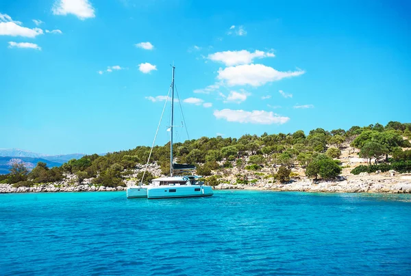 Turkuaz deniz sularında beyaz yelkenli yelkenli Katamaran yatı..