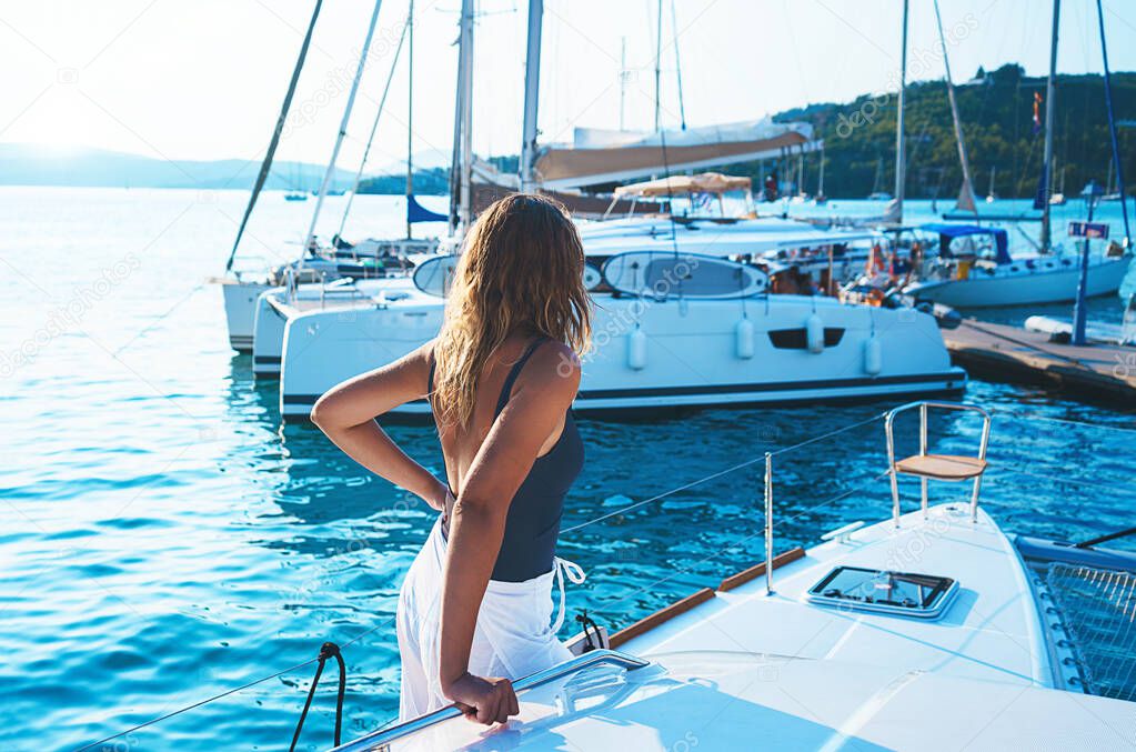 Happy young woman feels fun on the luxury sail boat yacht catamaran in turquoise sea in summer holidays on island Greece background.