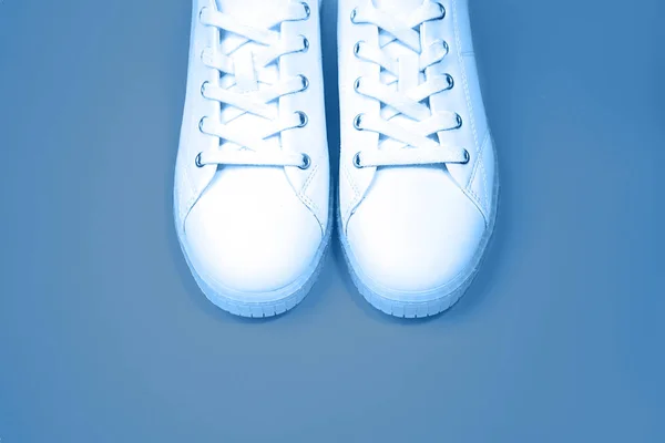 White sneakers are lying on a blue color background. — Stock Photo, Image