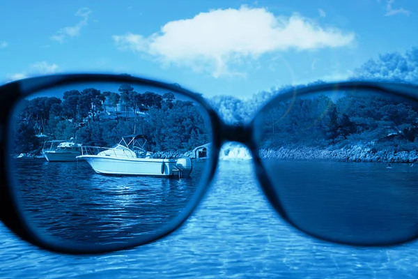 Guardando attraverso gli occhiali. Occhiali da sole contro cielo blu e mare . — Foto Stock