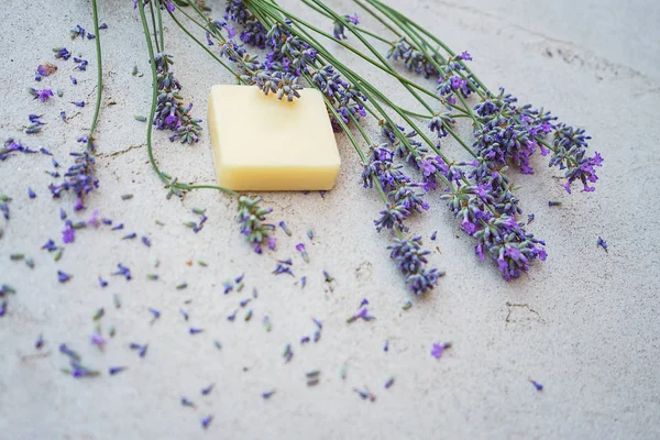 Lavendel bloemen en natuurlijke zeep voor lichaamsverzorging op beton achtergrond. — Stockfoto