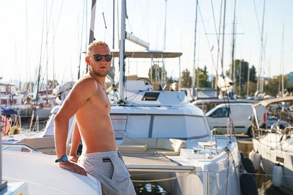 Happy young man feels happy on marina near the luxury sail boat yacht catamaran in summer holidays.
