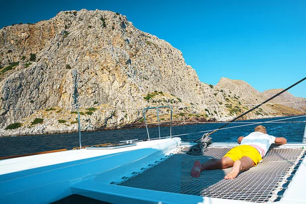 Boldog fiatalember úgy érzi, boldog a luxus vitorlás jacht katamarán türkiz tenger nyári szünidőben a szigeten. — Stock Fotó