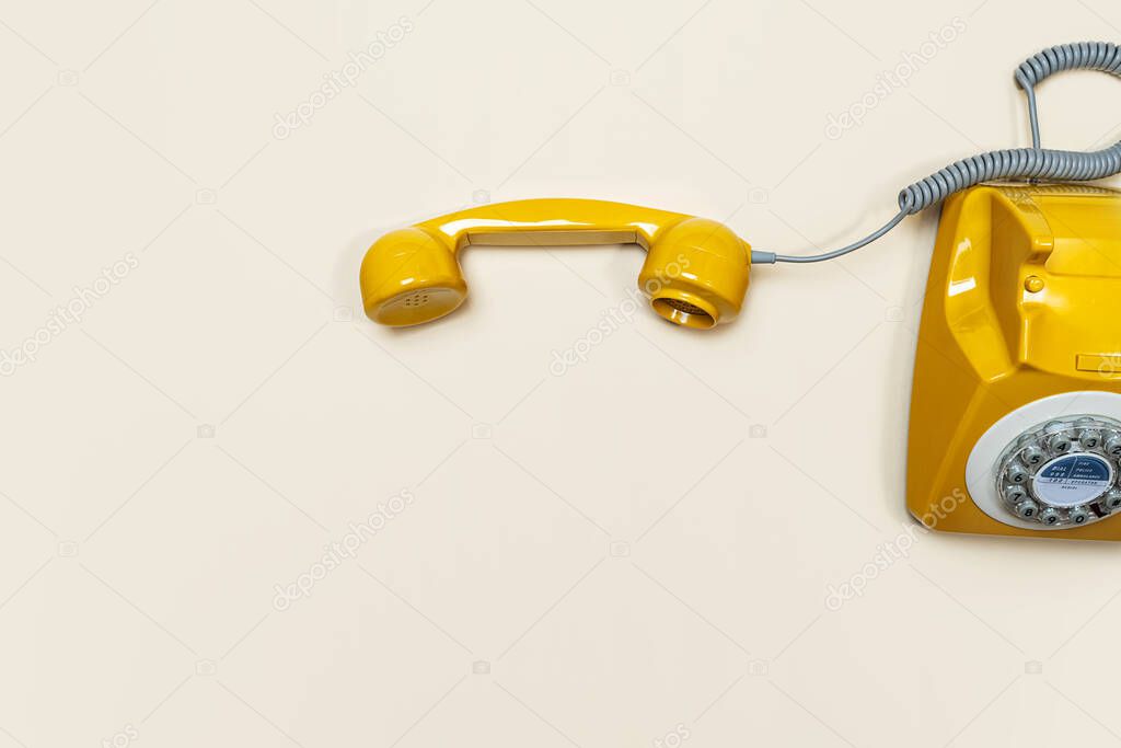 Old fashioned handset on beige color background. Modern retro style of rotary telephone.