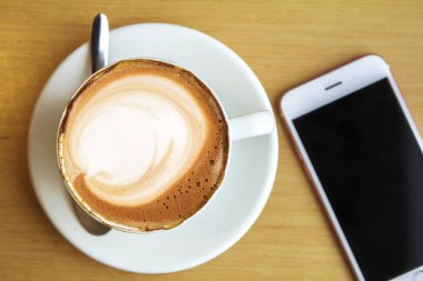 Seramik bardakta sıcak kahve kapuçino latte sanatının en üst görüntüsü.
