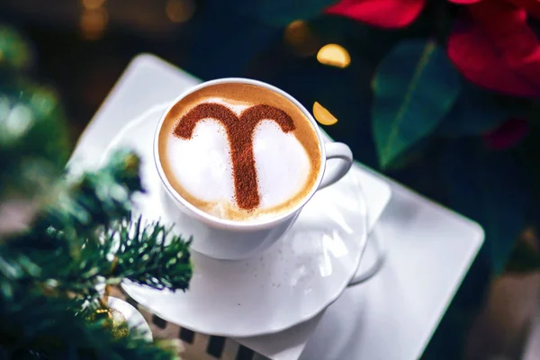 zodiac sign Aries on a foam of hot cappuccino in a white cup and stars on a dark table