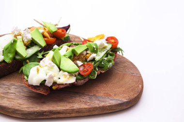 Ahşap tahtada avokado, peynir ve sebzeli bruschetalar. 