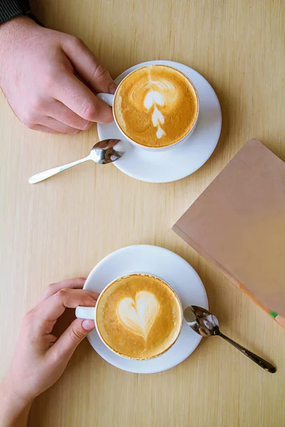 two people drinking coffee cappuccino with romantic latte art