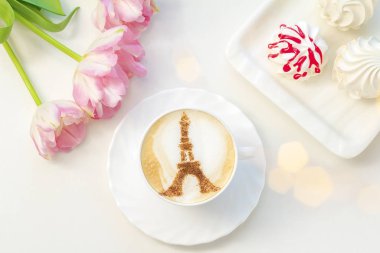 Beyaz bardakta kahve kapuçinosu ve beyaz köpüklü tarçın Eyfel kulesi deseni.