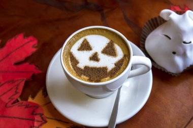 Bir fincan cadılar bayramı sembollü kapuçino. Süt köpüklü latte sanatı.