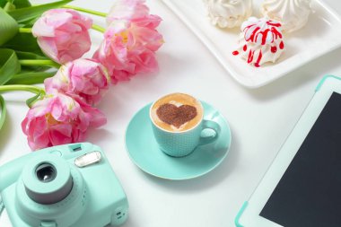  Sıcak kahve cappuccino ile latte romantik kalp sanatı. Pembe laleler ve tablet bilgisayar 