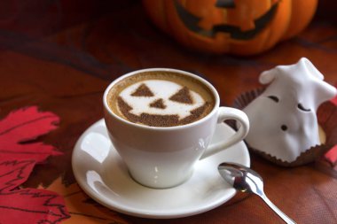 Bir fincan cadılar bayramı sembollü kapuçino. Süt köpüklü latte sanatı.