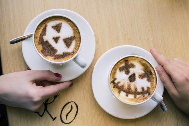 İki bardak kapuçino, üzerinde cadılar bayramı sembolü sütlü latte sanatı.