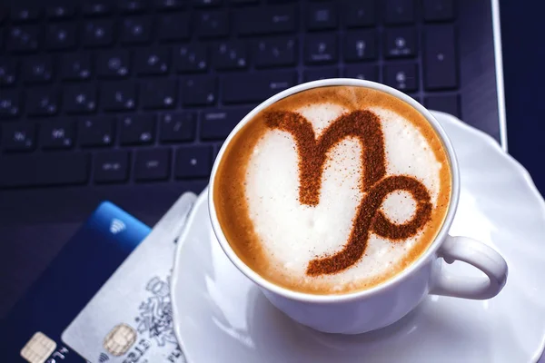 A cup of cappuccino coffee with a zodiac sign of Capricorn Cinnamon on milk foam