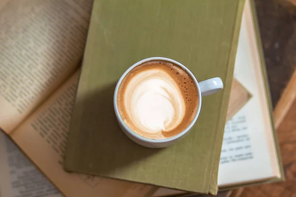 cup of latte or cappuccino coffee with a book in coffee shop