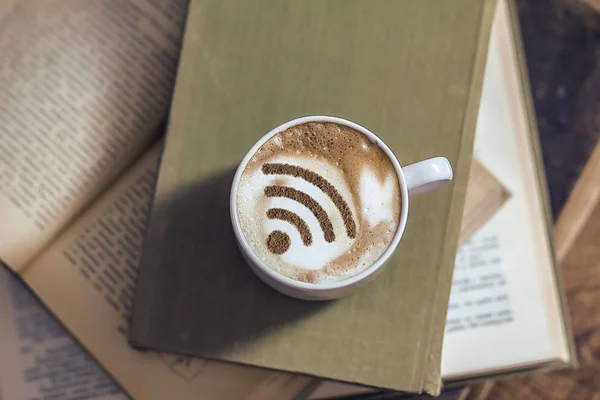 A cup of cappuccino coffee with painted cinnamon on milk foam with a wi-fi symbol