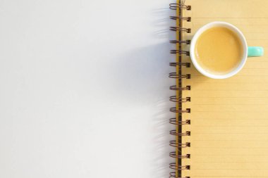 Kahve fincanda ve defter beyaz arkaplanda.