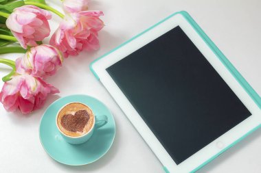  Sıcak kahve cappuccino ile latte romantik kalp sanatı. Pembe laleler ve tablet bilgisayar 