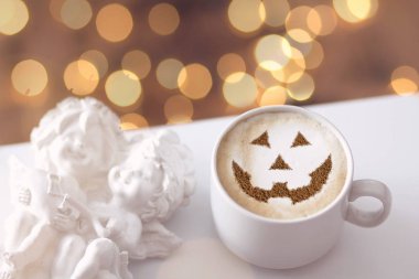 Bir fincan kapuçino. Süt köpüğünün üzerindeki tarçınlı cadılar bayramı sembolü.