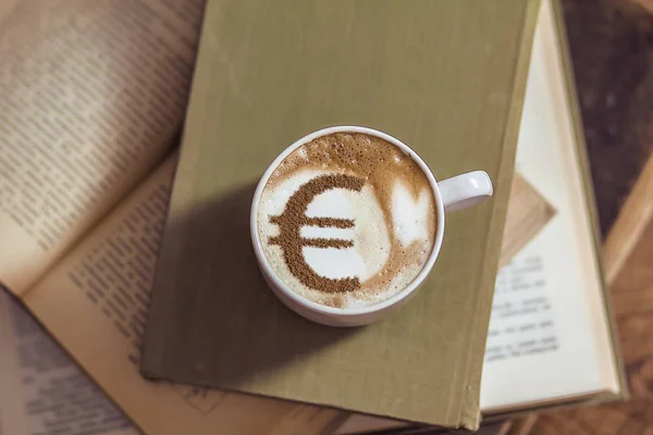 cup of coffee cappuccino with a picture of a Euro sign from cinnamon on milk foam