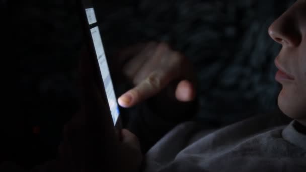 young man using his mobile phone on the bed in dark room. Thin guy playing his smartphone on the bed in dark room.